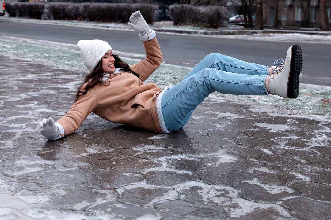 A woman lying on the ground in the snow, illustrating winter conditions relevant to therapy equipment leasing discussions.